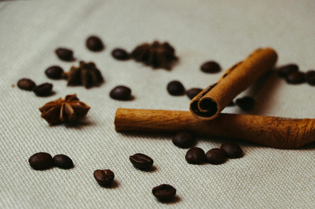 Close-up shot of cinnamon sticks, coffee beans, and star anise on a textured surface.