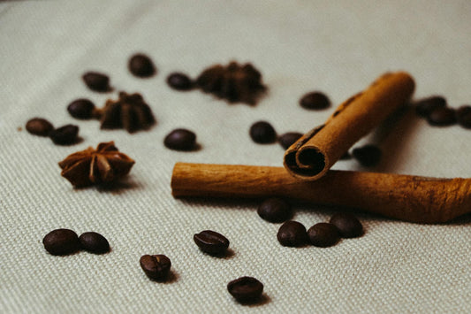 Close-up shot of cinnamon sticks, coffee beans, and star anise on a textured surface.