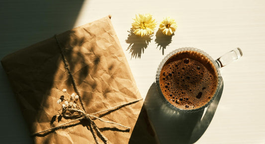 A charming scene with a coffee mug and gift wrapped in kraft paper on a sunlit table.