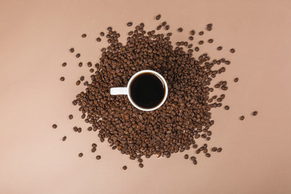 Cup of black coffee surrounded by roasted coffee beans representing UfuKoffee medium-dark roast coffee pods